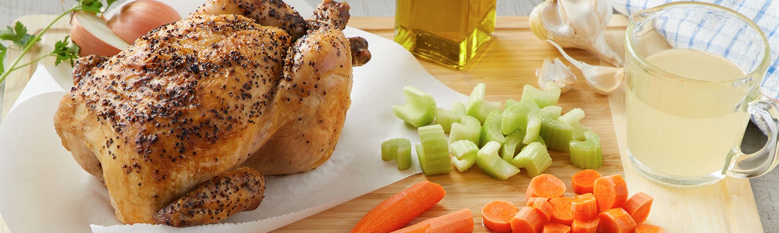 Whole cooked chicken with chopped carrots and celery on a table Whole cooked chicken with chopped carrots and celery on a table