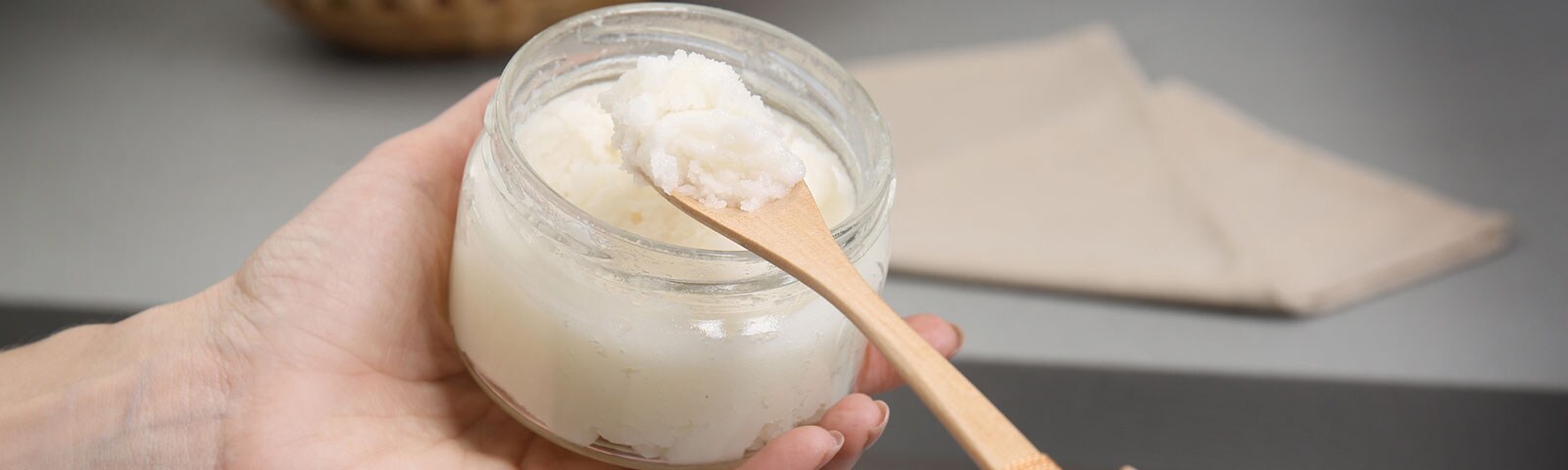 A pair of hands scooping coconut oil from a jar