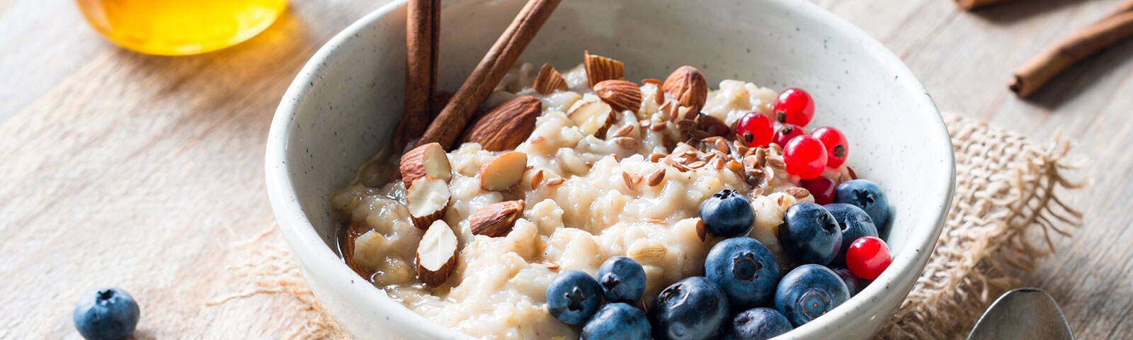 a bowl of oatmeal with almonds, blueberries and sticks of cinnamon