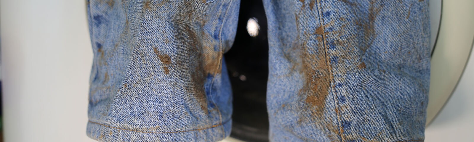 A pair of jeans covered with brown stains A pair of jeans covered with brown stains