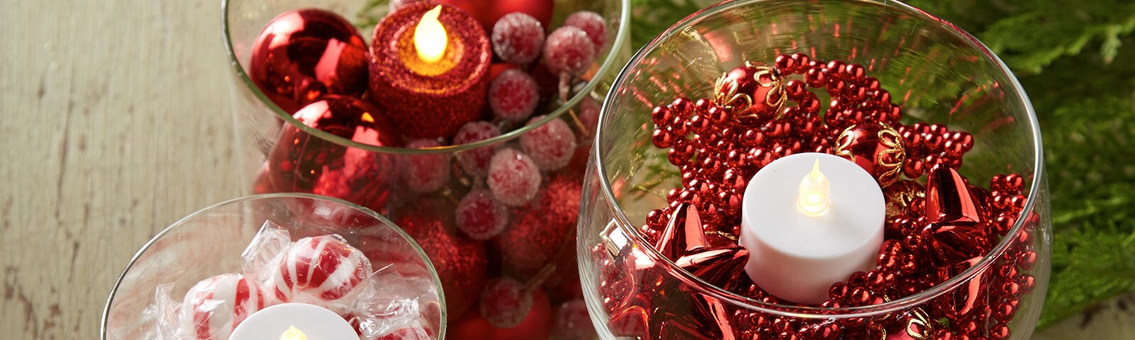Glass vases filled with red beads, peppermints and cranberries with tea lights placed in the middle Glass vases filled with red beads, peppermints and cranberries with tea lights placed in the middle