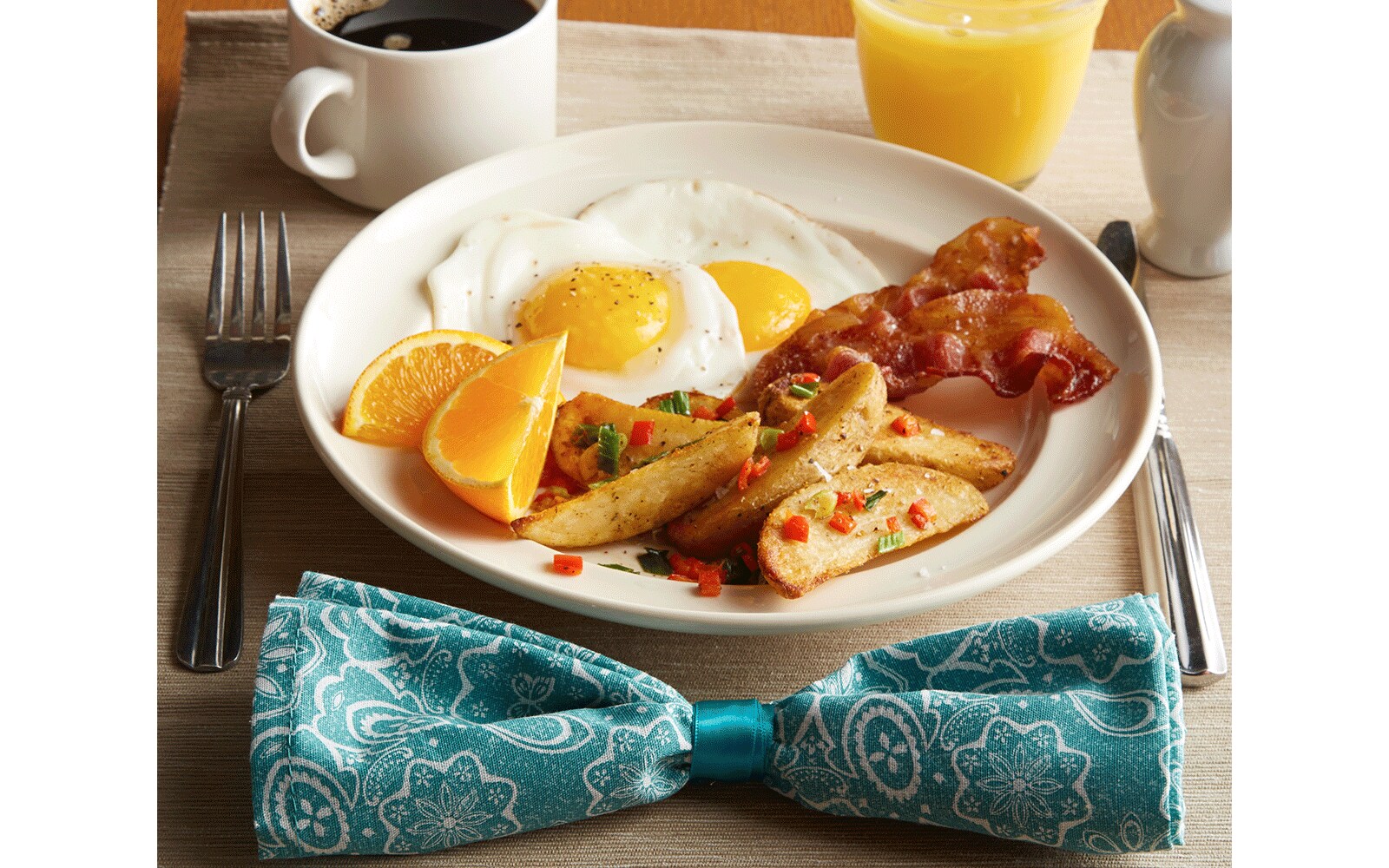 Breakfast including eggs and bacon on a plate with coffee and orange juice on a table Breakfast including eggs and bacon on a plate with coffee and orange juice on a table