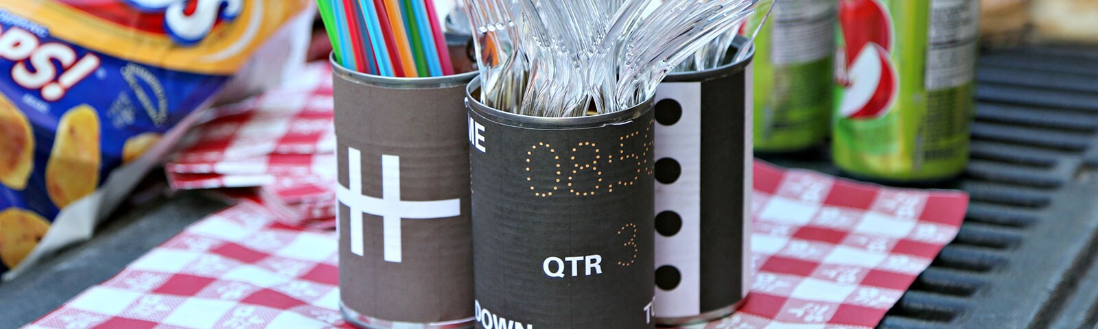Plastic silverware and colorful straws in tin can decorated as footballs Plastic silverware and colorful straws in tin can decorated as footballs