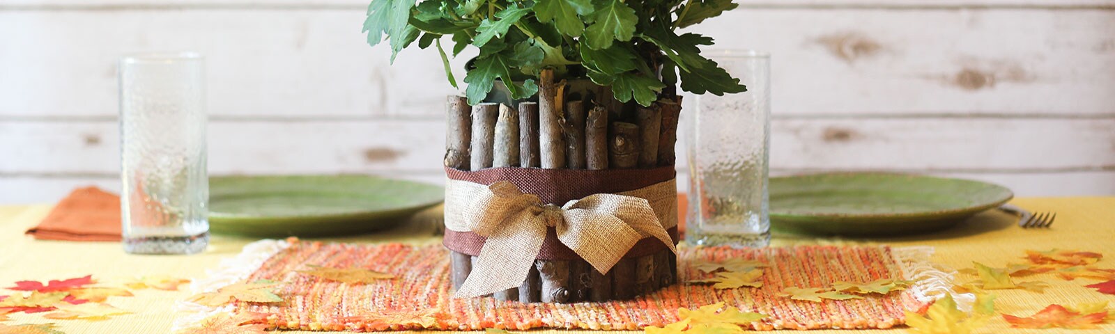 Finished DIY wood vase with a brown ribbon around the base and a potted plant inside on a dinner table Finished DIY wood vase with a brown ribbon around the base and a potted plant inside on a dinner table
