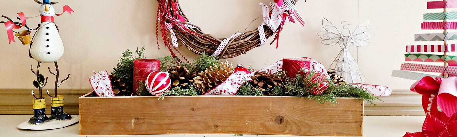 A wooden box on a mantle filled with evergreen clippings, ornaments, garland and festive candles A wooden box on a mantle filled with evergreen clippings, ornaments, garland and festive candles