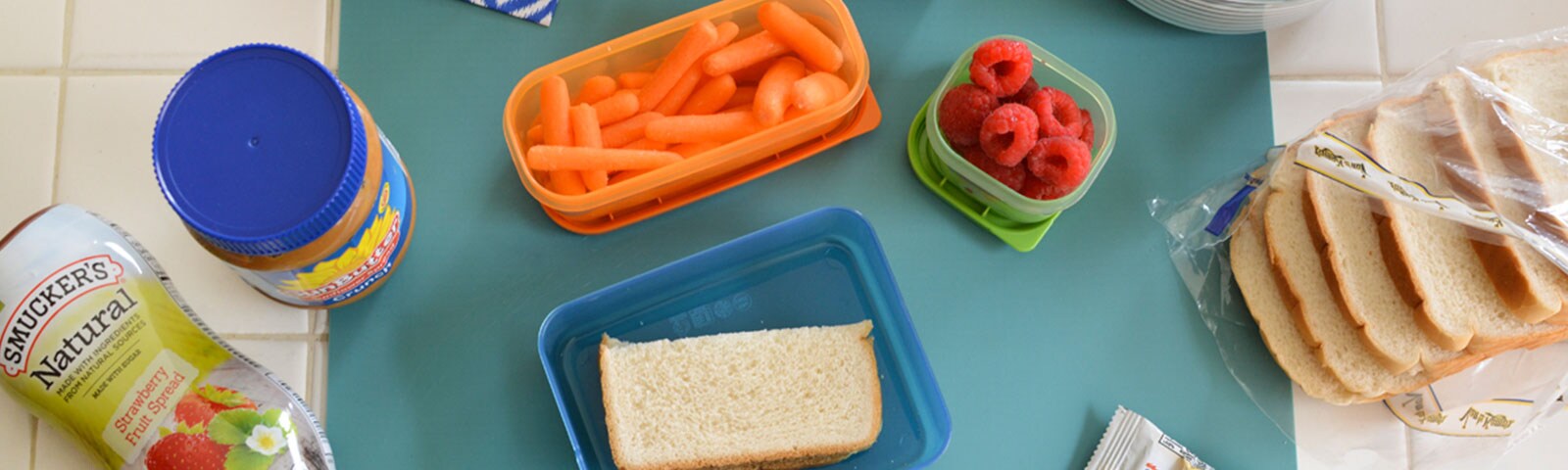 Lunch prep with a peanut butter and jelly sandwich, fruits and vegetables in reusable packing containers Lunch prep with a peanut butter and jelly sandwich, fruits and vegetables in reusable packing containers