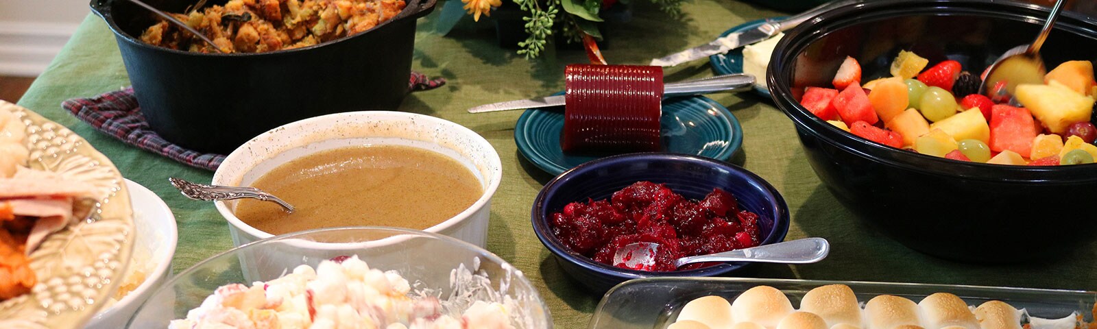 Thanksgiving potluck dishes like gravy and cranberry sauce on a table Thanksgiving potluck dishes like gravy and cranberry sauce on a table
