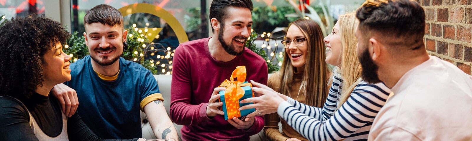 A group of friends exchanging gifts at a restaurant A group of friends exchanging gifts at a restaurant