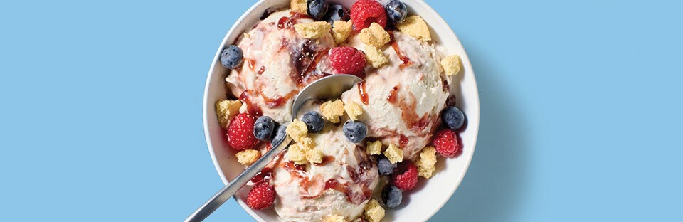 Vanilla ice cream sundae with mixed berry preserves, fresh berries and crushed shortbread cookies